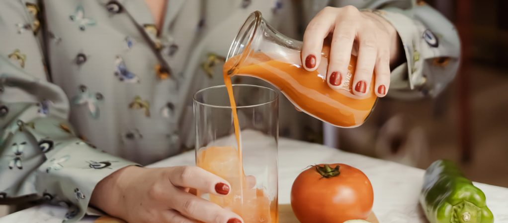 Serving gazpacho into a glass with ice cubes